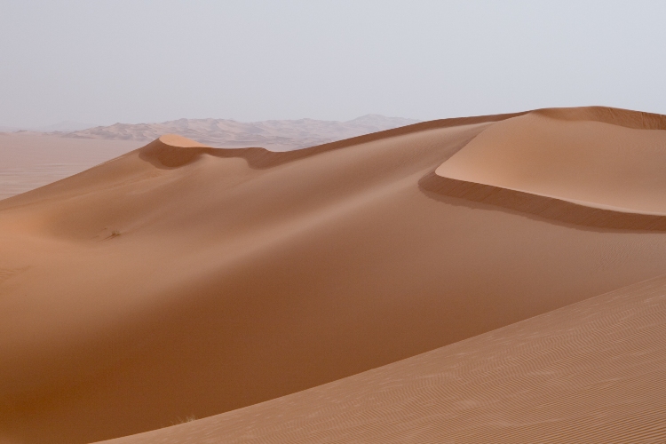 Písečné duny lybijské pouště. Jaký fenomén mohl způsobit zvýšení teploty pouštního písku na nejméně 1800° C a jeho odlití do obrovských pevných žlutozelených tabulí skla? (Wikipedia.org)